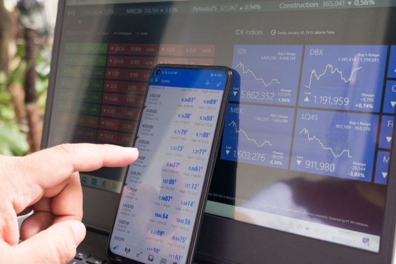 finger pointing at phone screen placed in front of a desktop screen