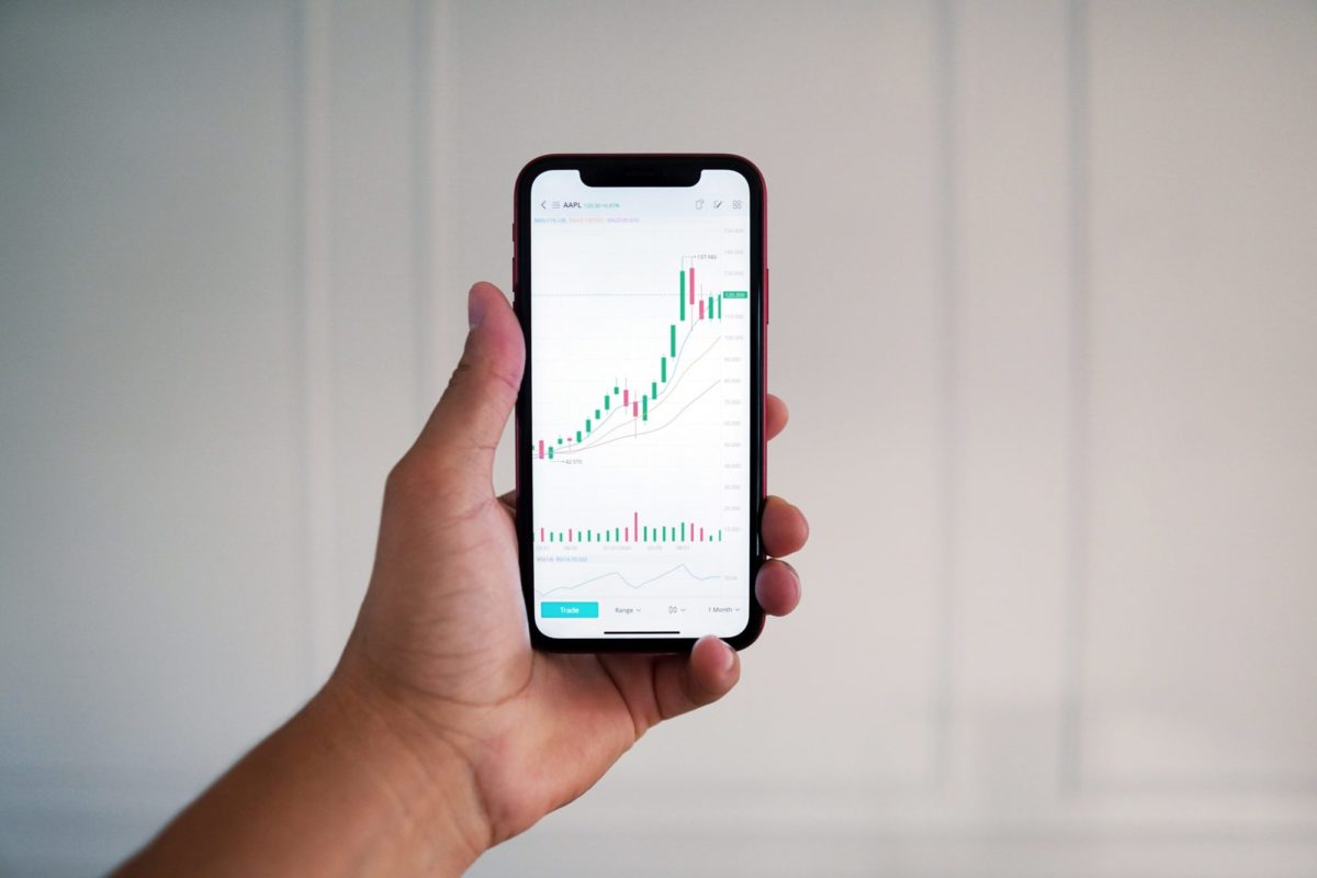 hand holding phone with trading information